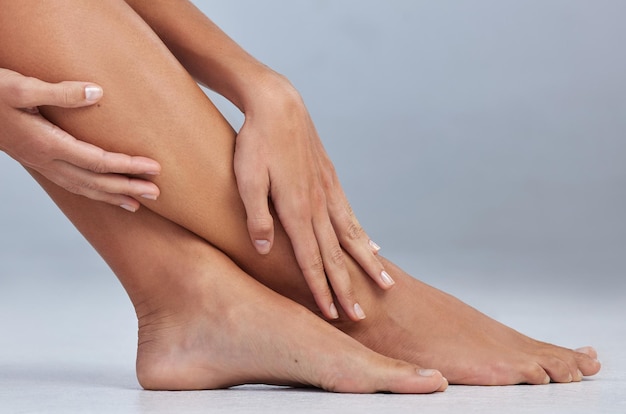 Regalati una pedicure Ritagliata di una donna irriconoscibile seduta da sola e che si tocca le gambe in studio