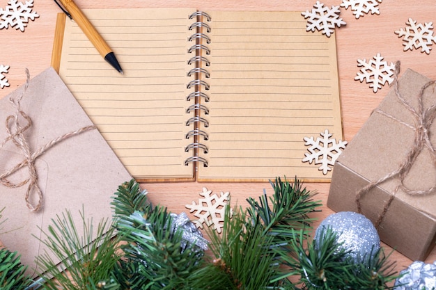 Regali di diario notebook aperto in bianco in scatole fatte a mano rami di abete e fiocchi di neve in legno Concetto di lista dei regali