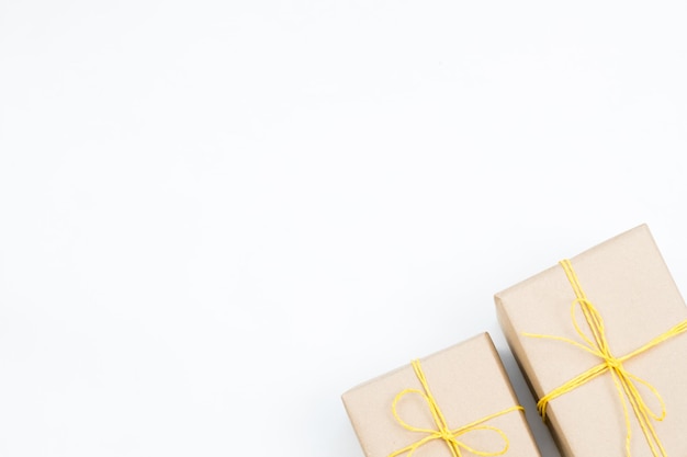 Regali di festa in scatole regalo avvolti in carta artigianale e legati con uno spago giallo due pacchetti su sfondo bianco con copyspace