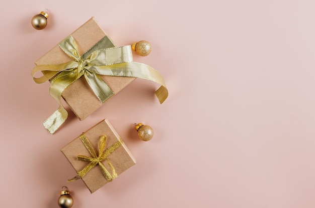 Regali di moda o scatole regalo con fiocchi dorati e palline su sfondo pastello polveroso Composizione piatta per compleanno Natale o matrimonio Vista dall'alto con spazio di copia