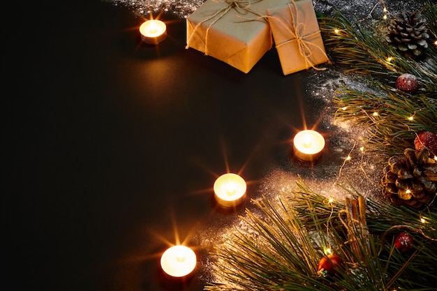 Regali di Natale, albero di Natale, candele, decorazioni colorate, stelle, palline su sfondo nero. Vista dall'alto. Copia spazio. Natura morta Piatto posare Capodanno