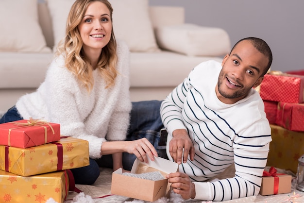 Regali di Natale. Bella allegra giovane coppia disimballaggio ai loro regali e sorridente divertendosi