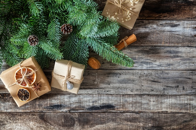 Regali di Natale creativamente avvolti e decorati in scatole dal brunch fresco dell'albero di Natale su superficie di legno scura, disposizione piana, spazio della copia