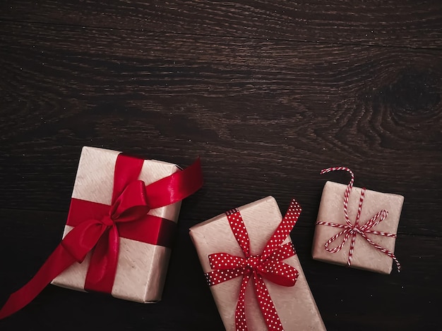 Regali di Natale e regali tradizionali per le vacanze classiche scatole regalo di Natale su fondo in legno presenti avvolte in carta artigianale con nastro rosso stile rustico vintage per le vacanze stagionali
