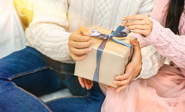 Regali di Natale nelle mani di un uomo e una donna, messa a fuoco selettiva.