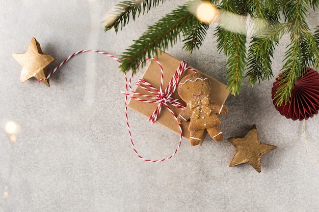 Regali e omino di pan di zenzero giacciono su sfondo bianco con rami di albero di natale