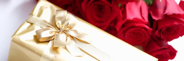 Regalo avvolto in oro e un mazzo di rose rosse