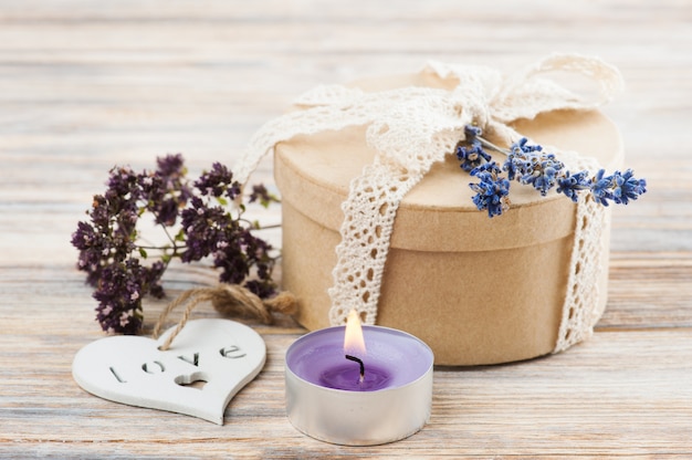 Regalo con fiocco in pizzo, fiore di lavanda e candela accesa