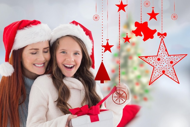 Regalo di apertura della figlia e della madre contro l'albero di Natale sfocato in camera