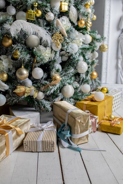 Regalo di festa sotto l'albero di Natale avvolto con spago e carta da regalo decorata con ghirlande e giocattoli.