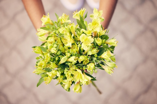 Regalo di fiori e persona con bouquet per ringraziamento sostegno o amore in una strada o strada della città Uomo o donna con un fiore di giglio giallo come regalo di ringraziamento compleanno o celebrazione