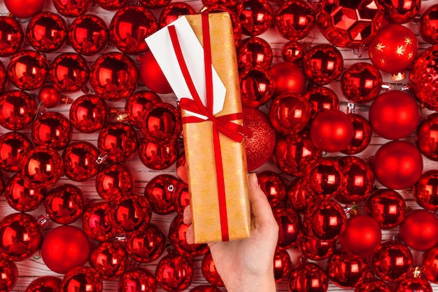 Regalo di Natale circondato da palline rosse luccicanti