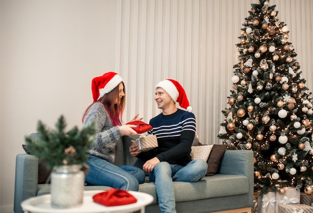 Regalo di Natale. Coppia felice in cappello di Babbo Natale con regalo di Natale e Capodanno a casa.