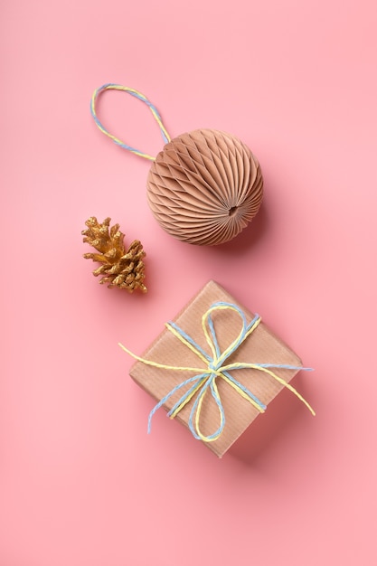 Regalo di Natale e palla di carta fatta a mano su sfondo rosa pastello