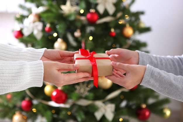 Regalo di Natale o Capodanno nelle mani contro un interno decorato