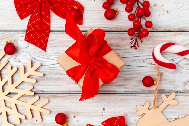 Regalo di natale rosso con decorazioni su fondo in legno