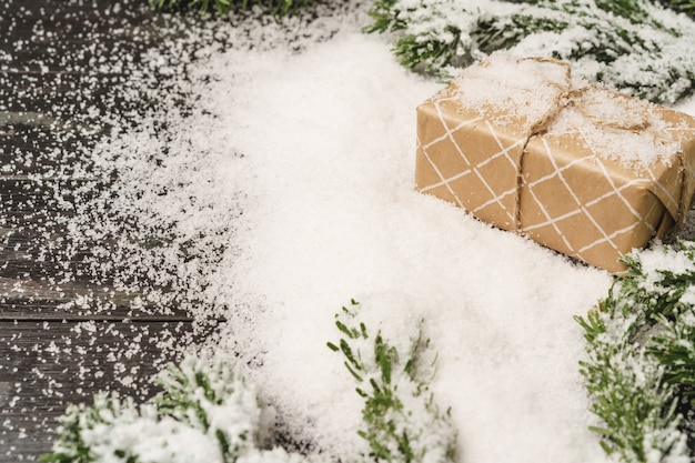 Regalo di Natale sul tavolo di legno spolverato di neve