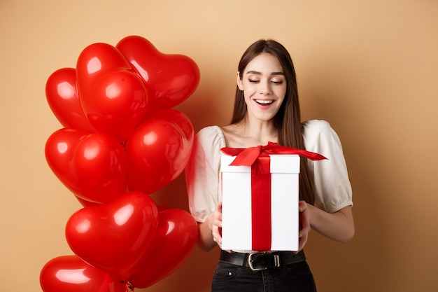 Regalo di San Valentino aperto donna felice, sorridendo eccitato e guardando la scatola attuale