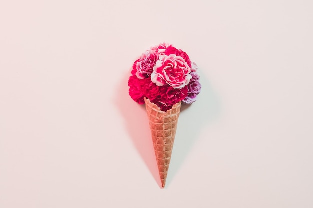 Regalo floreale concettuale Cono gelato con garofano rosa scuro su sfondo avorio