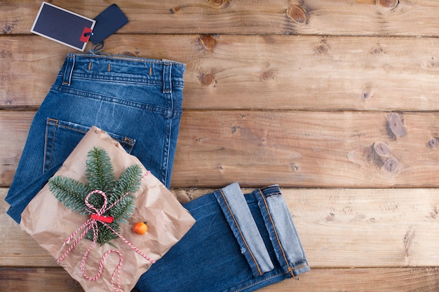 regalo, jeans e rami di abete rosso su un legno marrone