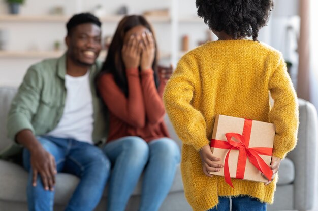 Regalo per mamma bambina nera che nasconde la confezione regalo dietro la schiena