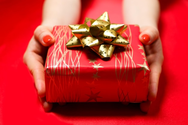 Regalo rosso con fiocco giallo nelle mani di una donna