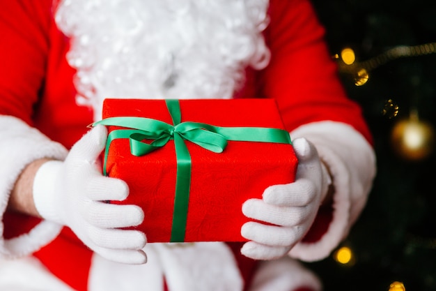 Regalo rosso in mani di Babbo Natale vicino a Natale