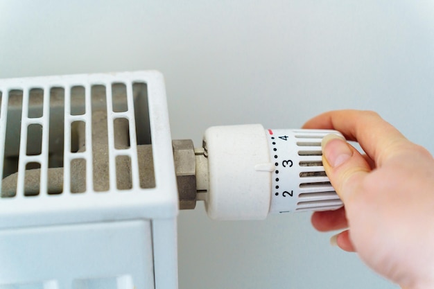 Regolatore a mano sul radiatore di riscaldamento che risparmia risorse ed energia termica a causa della crisi energetica