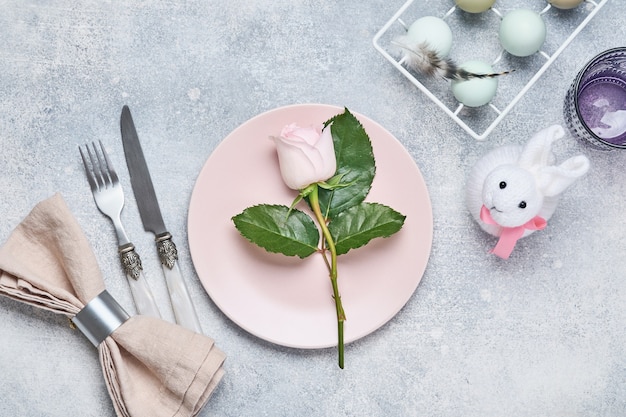 Regolazione della tabella di Pasqua con rosa rosa fresca sul tavolo di pietra grigia. Vista dall'alto. Cena di vacanza di Pasqua di eleganza.