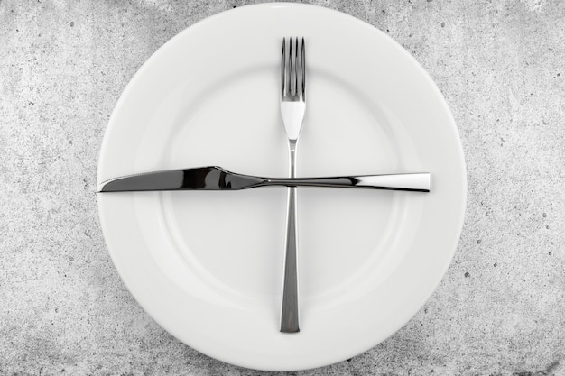 Regolazione della tabella, piatto vuoto, coltello e forchetta su un cemento leggero