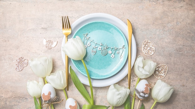 Regolazione della tavola di Pasqua con decorazioni floreali sulla tavola grigia.