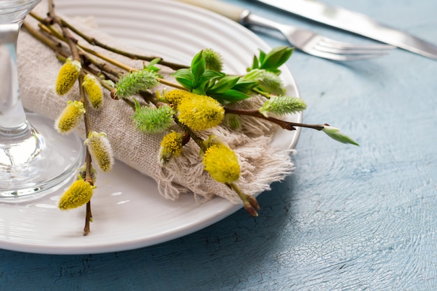 Regolazione della tavola di Pasqua della primavera su una tavola di legno blu con i fiori