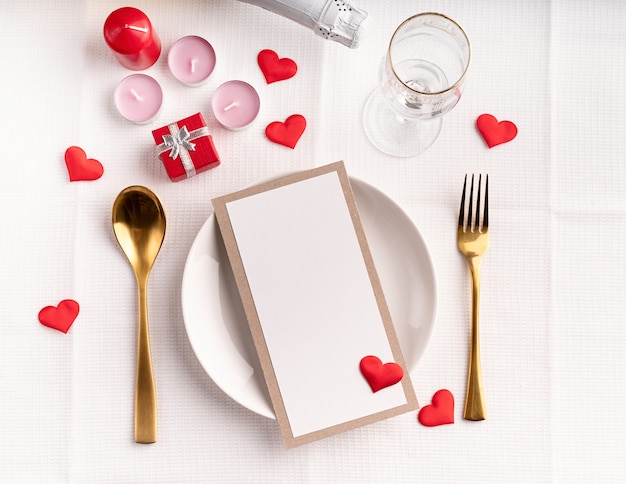Regolazione della tavola di San Valentino con menu, piatto, bottiglia di champagne vista dall'alto, mock up design