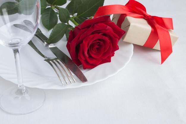 Regolazione festiva della tavola con una rosa rossa e un regalo