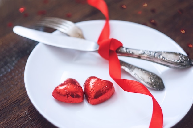 Regolazione festiva della tavola di San Valentino, modello con due caramelle di cioccolato di forma del cuore di rosso