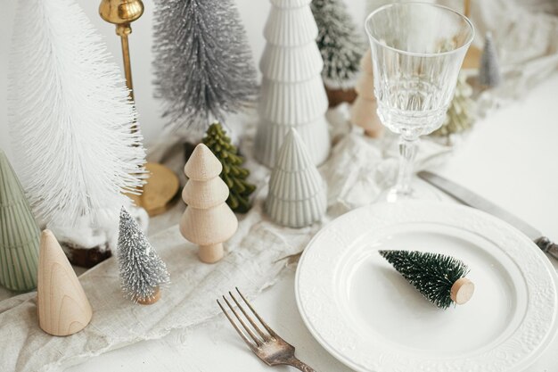 Regolazione moderna della tavola di Natale Piccolo albero di Natale sul piatto posate bicchieri arredamento festivo
