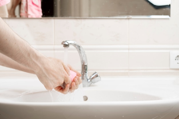 Regole di igiene personale, persona con un pezzo di mattone di sapone e lavarsi le mani sporche, protezione covid coronavirus