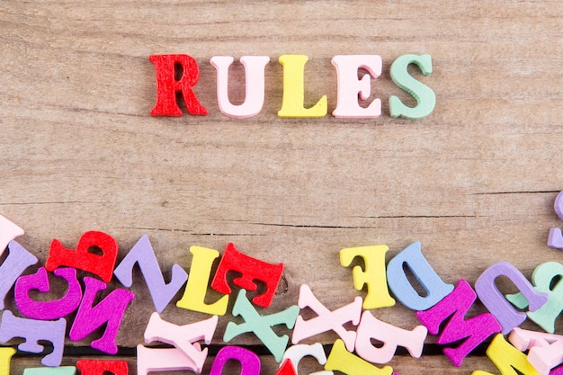 Regole di testo di lettere di legno colorate su uno sfondo di legno