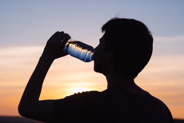 Reidrata il tuo corpo. maschio che beve una bottiglia d'acqua.