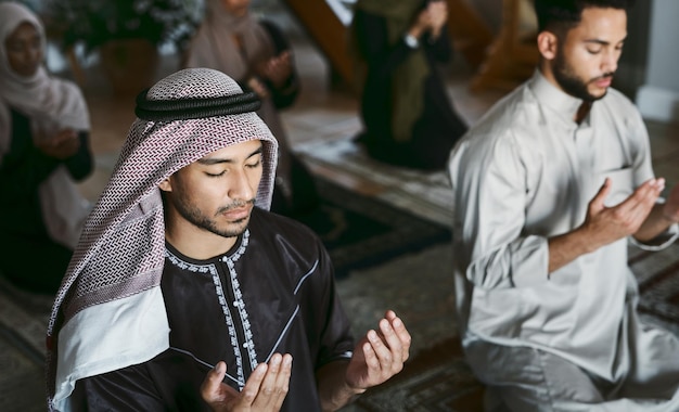 Religione Famiglia araba e musulmana che prega in ginocchio e adora insieme in una moschea islamica per onorare e Dio Un gruppo religioso tradizionale e spirituale di santi durante l'Eid Ramadan sui tappeti