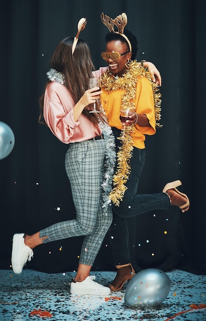 Rende la vita migliore Inquadratura integrale di due giovani donne attraenti in piedi e che si abbracciano durante una festa di Capodanno