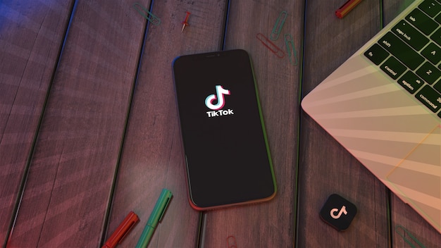 Rendering 3D di uno smartphone che mostra il logo dell'app Tik Tok su un desktop in legno