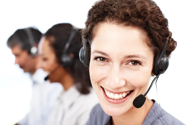 Renderti la vita più facile è il suo lavoro Ritratto del primo piano di un professionista sorridente del call center con i colleghi seduti sullo sfondo