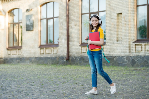 Rendi l'apprendimento più piacevole. Bambino indossare le cuffie all'aperto. La moderna tecnologia nell'istruzione. Scuola a distanza. Corsi di lingua straniera. Capacità di ascolto. Stile di vita moderno, copia spazio.