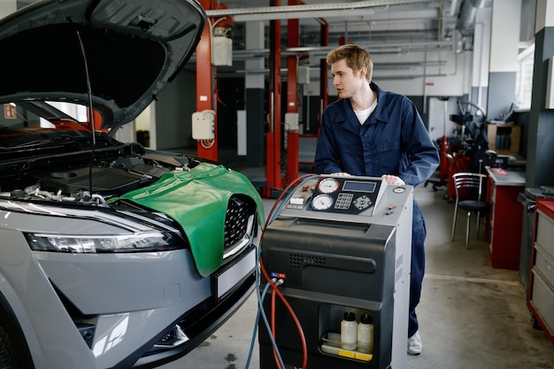 Reparatore in un garage che effettua la manutenzione dell'aria condizionata o del climatizzatore