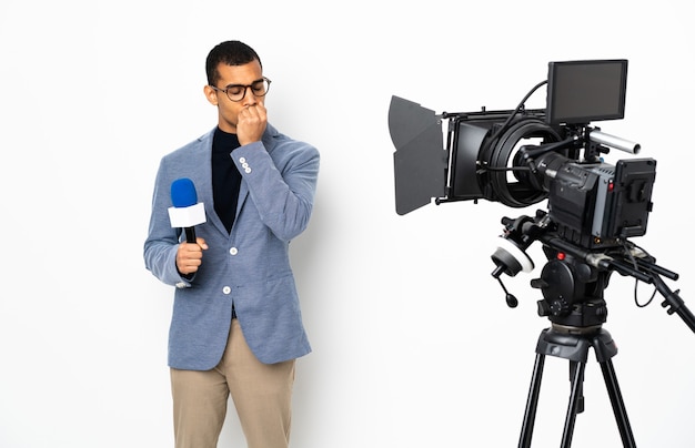 Reporter uomo afroamericano in possesso di un microfono e segnalazione di notizie su bianco isolato avendo dubbi