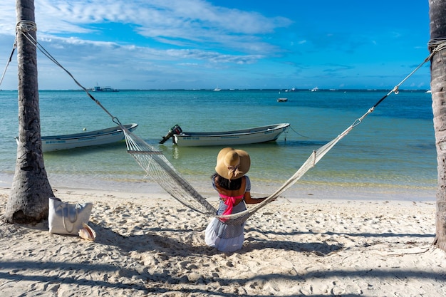 Repubblica Dominicana di Punta Cana una ragazza con un cappello sull'oceano con acqua turchese e palme