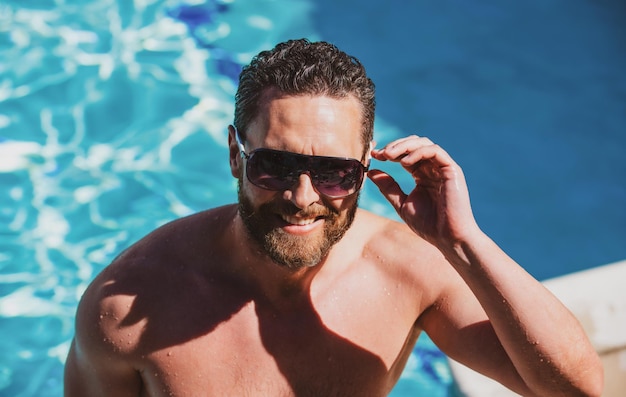 Resort estivo in piscina Bell'uomo in vacanza estiva Uomo con occhiali da sole che si rilassa in piscina