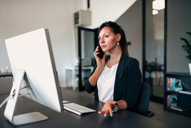 Responsabile femminile arrabbiato che parla sul telefono nell&#39;ufficio.