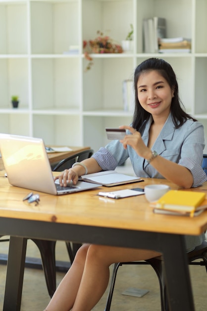 Responsabile femminile che utilizza un computer portatile e tiene un concetto di pagamento con carta di credito con carta di credito